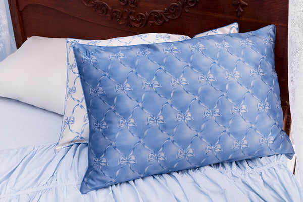 Blue silk pillowcase with bow pattern on a bed