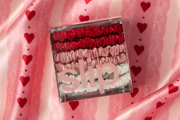 Box of 'slip' products on a pink fabric background with heart patterns