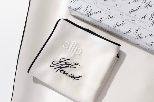 Close up of 'just married' embroidery in black on a white silk pillowcase.