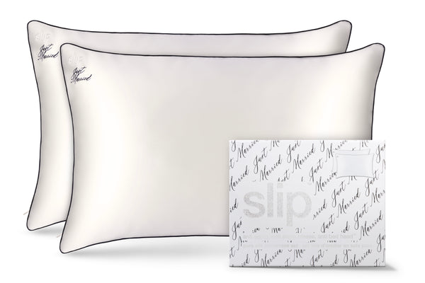 A set of two white pillowcases with black piping and a 'just married' text design, displayed with slip logo packaging.