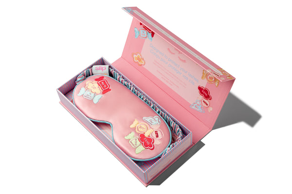 Pink eye mask with decorative elements in an open box on a white background