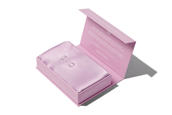 A lilac slip silk queen pillowcase in open branded packaging on a white background.