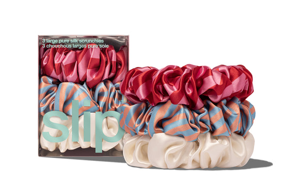 A set of large scrunchies in various colors including blue, red, and white, displayed in a box with the brand name 'slip' visible.