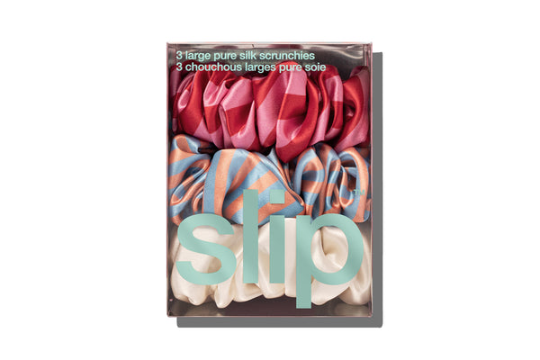 A set of large scrunchies in various colors including blue, red, pink and white in slip packaging on a white background.