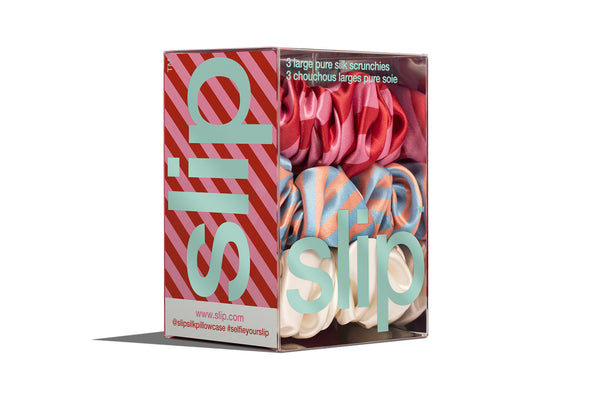 A set of large scrunchies in various colors including blue, red, pink and white in slip packaging on a white background.