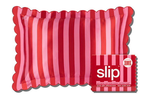 A striped pink slip silk pillowcase with a scalloped edge with brand slip packaging on a white background.