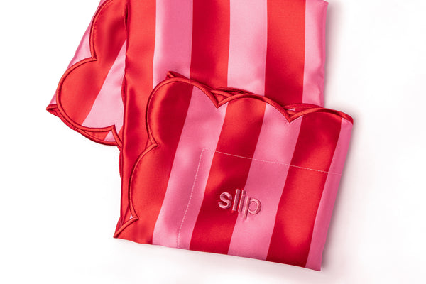 A striped pink slip silk pillowcase showcasing 'slip' embroidery.