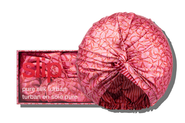 A red and pink striped silk turban or bonnet with a twist detail, displayed both outside and in a box.