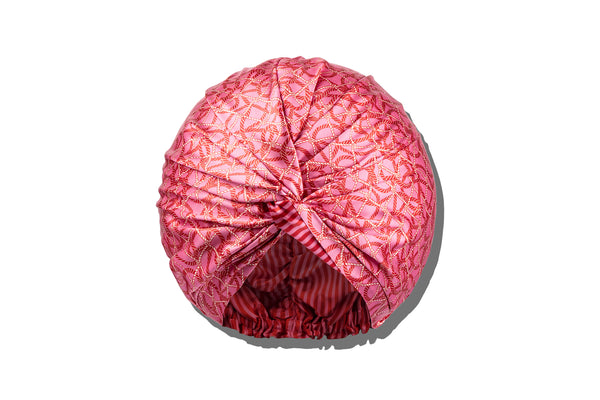 A red and pink nautical themed silk turban or bonnet with a twist detail.