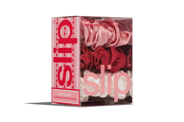 Box of slip scrunchies with red and pink scrunchies on a white background