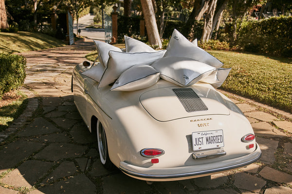 White slip pure silk pillowcases with black piping and 'just married' embroidery in the back of a white vintage car.