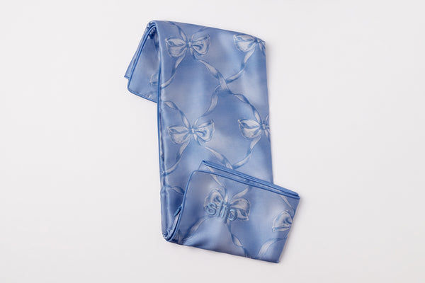 Blue silk pillowcase fabric with bow pattern on a light gray background