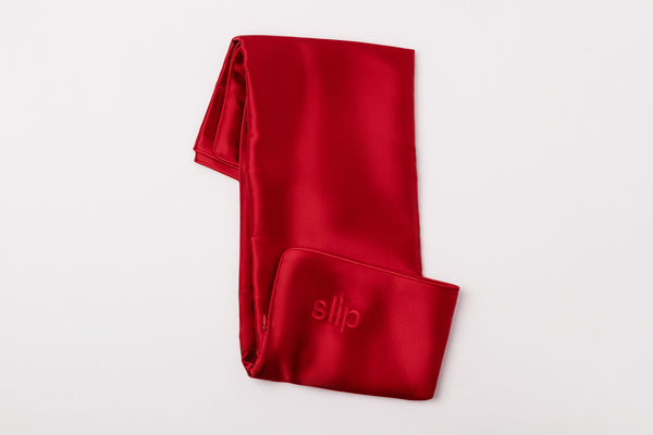 Red silk pillowcase with 'slip' embroidery on a white background