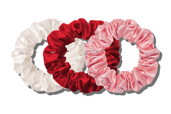 Set of three silk hair scrunchies in white, red, and pink on a white background